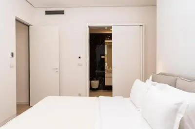 a white bedroom with a white bed with white pillows at Dukley Montesun Apartments in Budva
