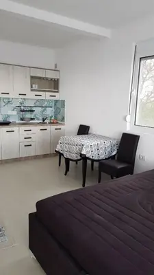 a bedroom with a table and two chairs and a kitchen at Apartment 7 in Bar, Susanj