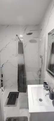 a white bathroom with a sink and a mirror at Sea apartman in Bar