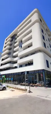 a large white building with a car parked in front of it at Sea apartman in Bar