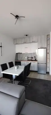 a kitchen with a table and chairs and a refrigerator at Sea apartman in Bar