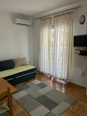 a living room with a couch and a large window at Sunny stay Budva in Rafailovici