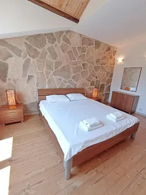 a bedroom with a bed and a stone wall at Spacious apartment Kotor in Kotor