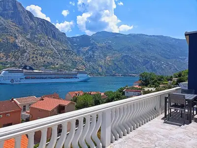 a cruise ship on the water with mountains at Spacious apartment Kotor in Kotor