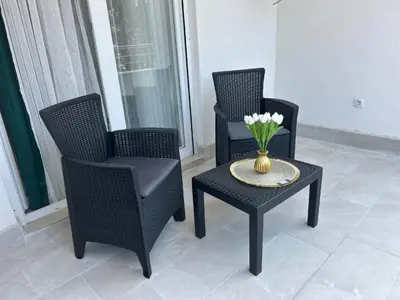 two chairs and a table with a vase with flowers on it at Pearl Wave-Apartment in Ulcinj