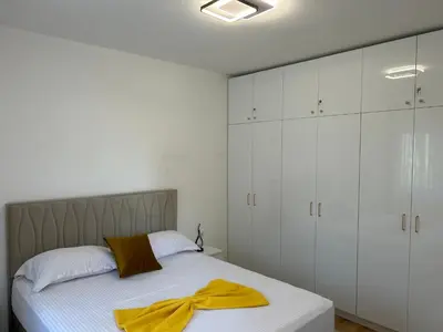 a bedroom with white cabinets and a bed with a yellow bow on it at Pearl Wave-Apartment in Ulcinj