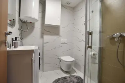 a bathroom with a toilet and a glass shower at Comfy one-bdr apartment Sara in Budva