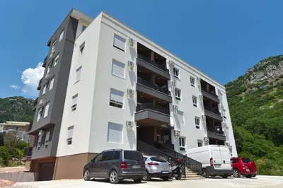 a white building with cars parked in front of it at Comfy one-bdr apartment Sara in Budva