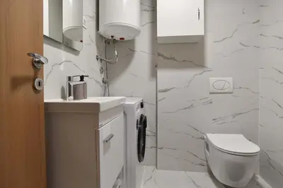 a white bathroom with a toilet and a sink at Comfy one-bdr apartment Sara in Budva