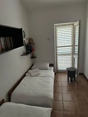 a bedroom with two beds and a television on the wall at Iskra house - Perazica Do in Perazića Do