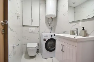 a white bathroom with a washing machine and a sink at Comfy one-bdr apartment Staša in Budva
