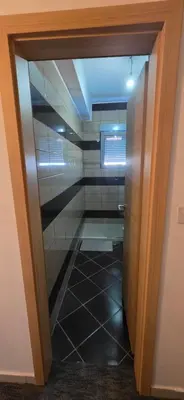 a glass door leading into a bathroom with a tile floor at KASIJA Apartman in Podgorica