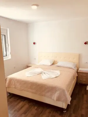 a bedroom with a large bed with white sheets at Delfini Holiday Homes in Ulcinj