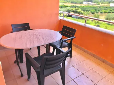 a table and chairs sitting on a balcony with a window at Delfini Holiday Homes in Ulcinj