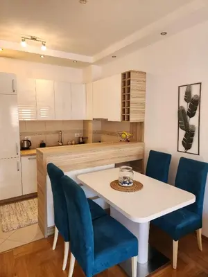 a kitchen with a white table and blue chairs at MiraBlu - New Modern Apartment - FREE parking in Budva
