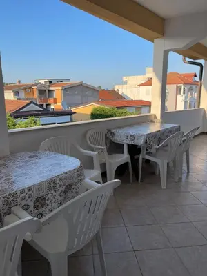 a patio with tables and chairs on a balcony at Apartmani Arieta in Donji Štoj