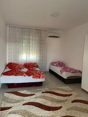 two beds in a bedroom with red sheets and a rug at Apartmani Arieta in Donji Štoj
