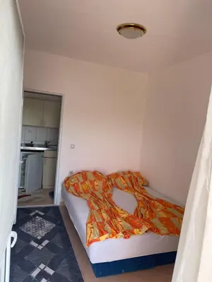 a small bedroom with a bed with an orange comforter at Apartmani Arieta in Donji Štoj