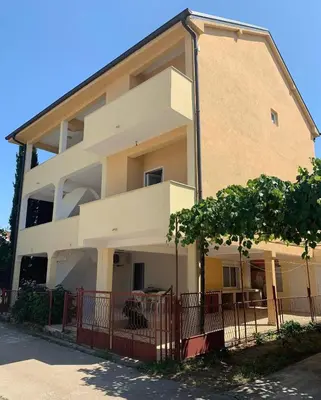 a large white building with a fence in front of it at Apartmani Arieta in Donji Štoj