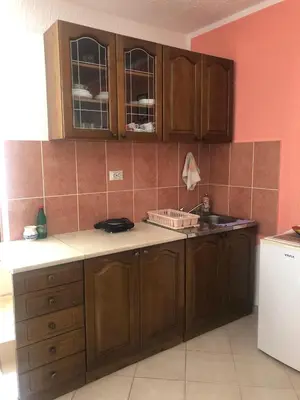 an empty kitchen with wooden cabinets and a sink at Apartmani Marina Sutomore in Sutomore