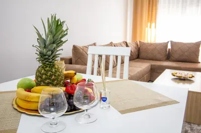 a plate of fruit on a table with two wine glasses at Apartment Numa - Ulcinj in Ulcinj