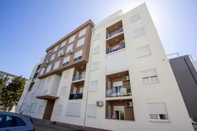 an apartment building with balconies and a car parked in front at Apartment Numa - Ulcinj in Ulcinj