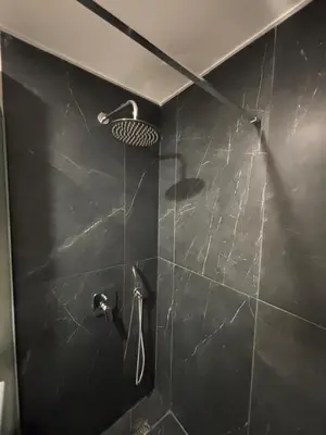 a bathroom with a shower with a black wall at Una Dobra Voda in Dobra Voda