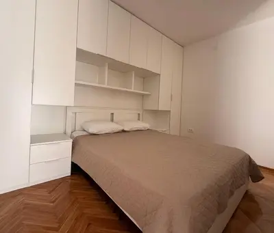 a bedroom with a large bed and white cabinets at Itana by the sea in Budva