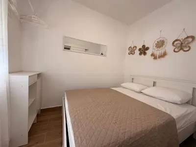 a white bedroom with a bed and a window at Itana by the sea in Budva
