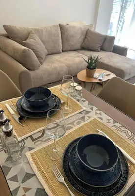 a table with plates and wine glasses and a couch at Tara in Bar