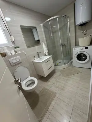 a bathroom with a toilet and a shower and a washing machine at Tara in Bar