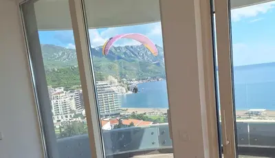 a paraglider flying over the ocean from a window at Skyline sea view apartment in Becici