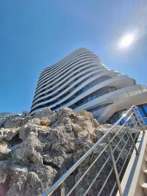 a tall building with a rock in front of it at Skyline sea view apartment in Becici