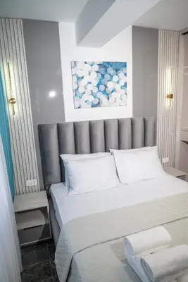 a bedroom with a large bed with a gray headboard at Urban Nest Apartment in Ulcinj