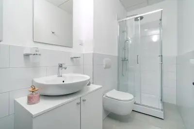 a white bathroom with a sink and a shower at TQ City Apartments in Radanovići