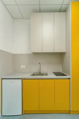 a kitchen with white and yellow cabinets and a sink at TQ City Apartments in Radanovići