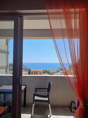 a room with a chair and a view of the ocean at Apartman More i Nebo in Petrovac na Moru