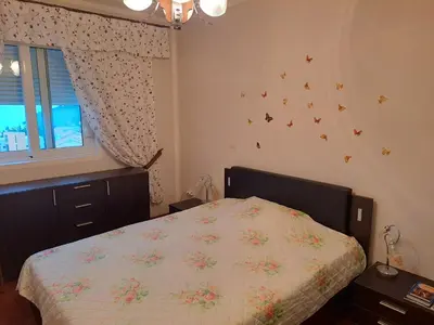 a bedroom with a bed and a window with butterflies on the wall at Apartman More i Nebo in Petrovac na Moru