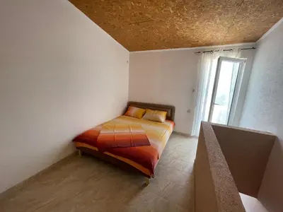 a bedroom with a bed in a room with a window at Apartmani Ilić in Utjeha