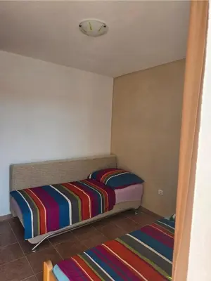 a small bedroom with a bed and two rugs at Ekilo in Dobra Voda