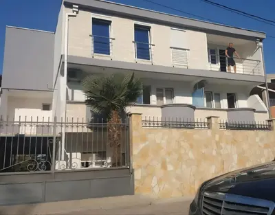 a man standing on the balcony of a white house at Ekilo in Dobra Voda