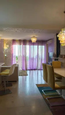 a living room with a table and chairs and pink curtains at Rezevici AZUR in Budva