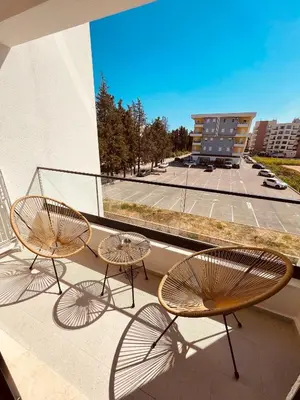 two chairs and tables on a balcony with a building at Apartments Buongiorno in Ulcinj