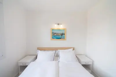 a bedroom with white walls and a bed with white pillows at Holiday Home Soul