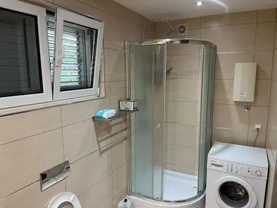 a bathroom with a shower and a washing machine at Villa Susanj in Bar