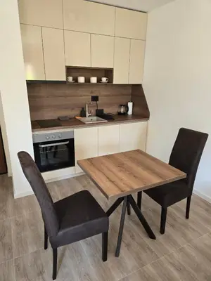 a kitchen with a wooden table and two chairs at Apartmani Kralj Bar in Bar