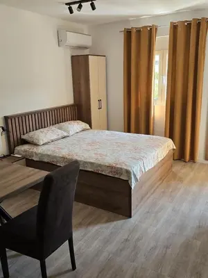 a bedroom with a large bed and a chair at Apartmani Kralj Bar in Bar