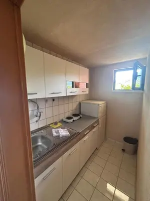 a small kitchen with white cabinets and a sink at Apartman MK in Kruče
