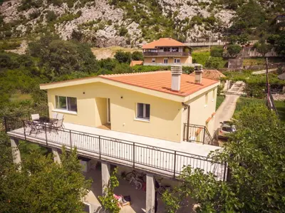 a yellow house on a bridge with a mountain at Dejana Apartments in Kotor