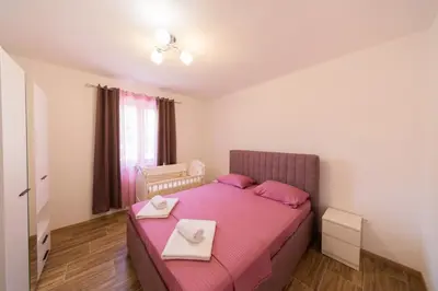 a small bedroom with a pink bed with two towels on it at Dejana Apartments in Kotor